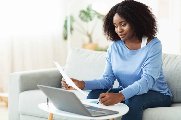 Donna nera firma documenti che lavorano sul computer portatile a casa — Foto Stock