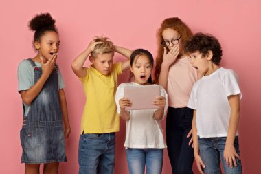 Tablet bilgisayarına birlikte bakan kızlar ve erkekler, pembe arka planda şok edici haberler öğreniyorlar.