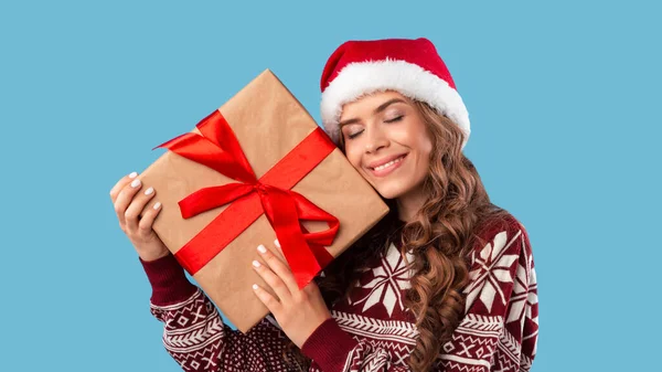 Vacaciones de invierno. Hermosa joven sosteniendo enorme regalo de Navidad sobre fondo azul — Foto de Stock