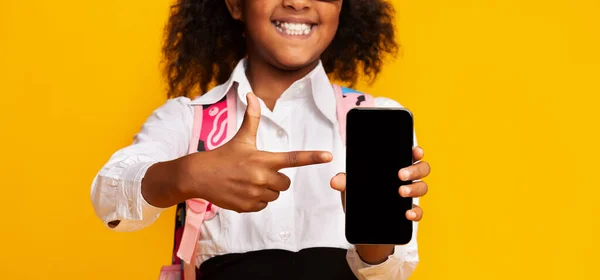Black Schoolgirl Showing Empty Smartphone Screen, Yellow Background, Cropped