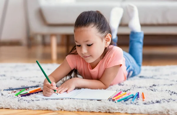 Niedliches chinesisches Kind skizziert mit Bleistiften das Wochenende zu Hause — Stockfoto
