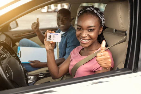 Chica africana feliz con licencia de conducir mostrando el pulgar hacia arriba —  Fotos de Stock