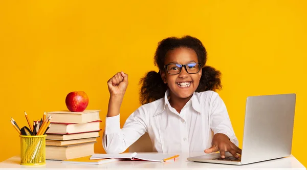 Дівчинка з афро - американської школи на ноутбуку піднімає руку, жовте тло — стокове фото