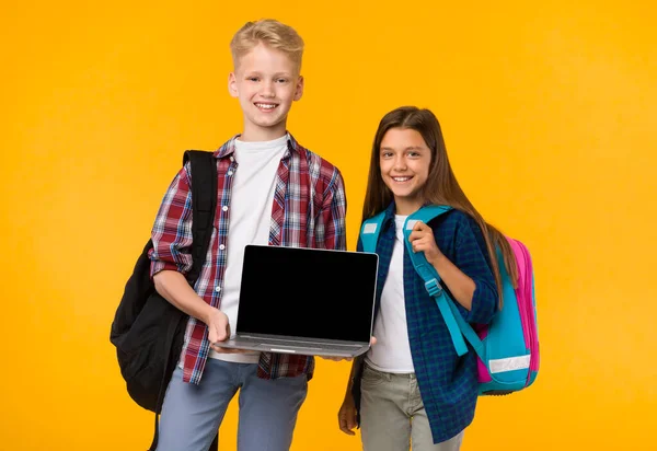 Schuljunge und Mädchen zeigen Laptop-Bildschirm vor Kamera — Stockfoto