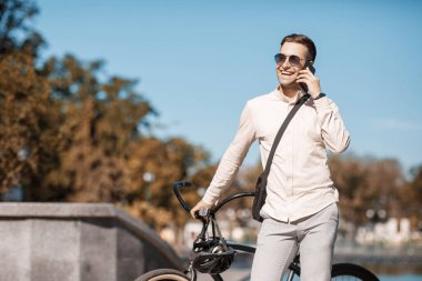Parktaki yakışıklı hippi. Bisikletli bir işadamı telefonda konuşuyor.