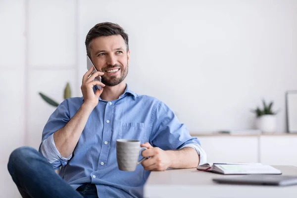 Break At Work. Relaxed Office Employee Talking On Cellphone And Drinking Coffee