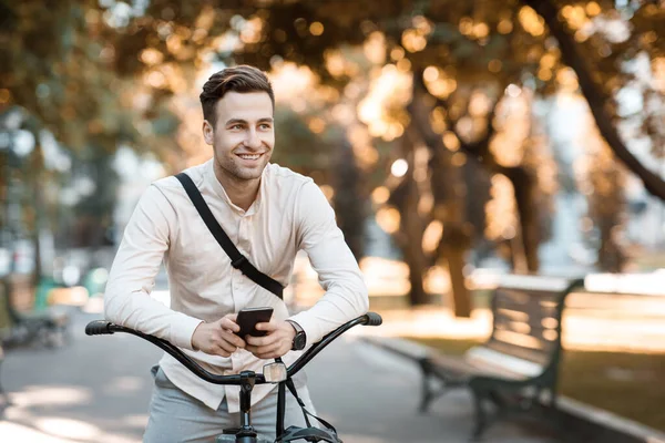 거리 스타일. 젊고 세련 된 청년이 자전거를 타고 앉아서 전화로 문자를 하고 있다 — 스톡 사진