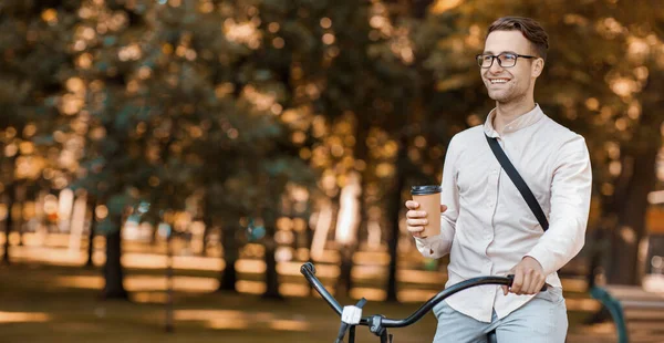 Passeio moderno para a cidade. Sorrindo cara em óculos com xícara de café passeios de bicicleta — Fotografia de Stock