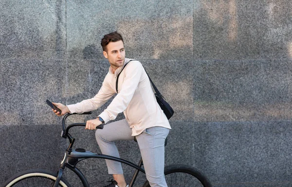 Ecologisch transportconcept. Serieuze man met tas rijdt op de fiets en kijkt weg — Stockfoto