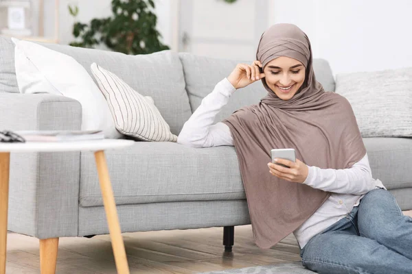 Millennial Arabic Girl mit Kopftuch nutzt Smartphone zu Hause, SMS mit Freunden — Stockfoto