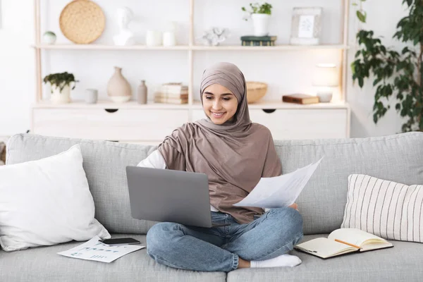 Ministerio del Interior. Mujer árabe ocupada trabajando con el ordenador portátil y documentos en el sofá — Foto de Stock