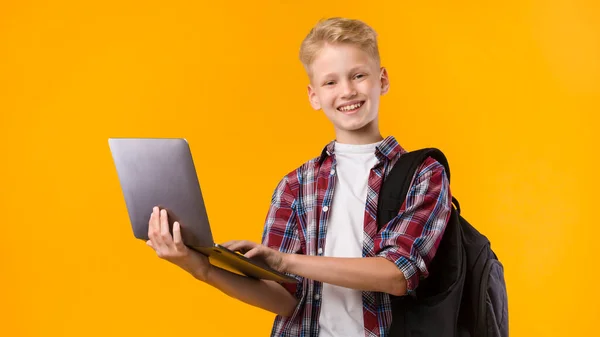Szczęśliwy facet trzyma laptopa w żółtym studio — Zdjęcie stockowe