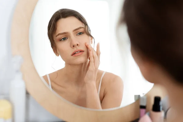 Bouleversé jeune femme regarder miroir, vérifier son visage peau — Photo