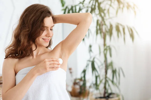 Wanita cantik muda menggunakan deodoran di kamar tidur — Stok Foto