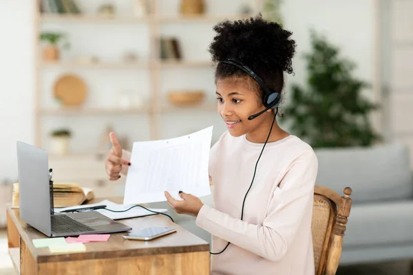 Chica en el ordenador portátil que muestra la tarea a la cámara web en casa — Foto de Stock