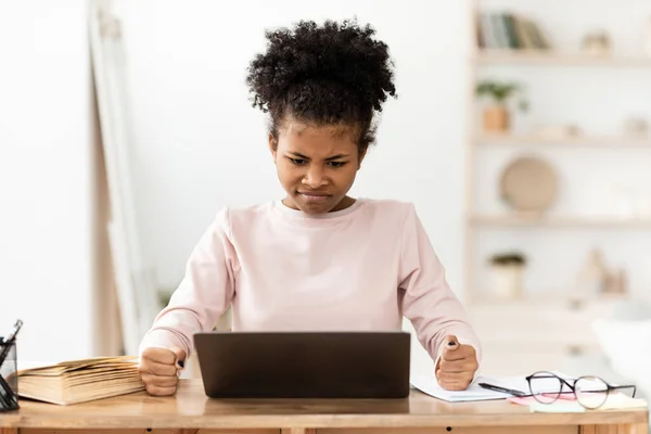 Kızgın Siyah Kız Dizüstü bilgisayara bakıyor. Kapalı alanda yumruklarını sıkıyor. — Stok fotoğraf