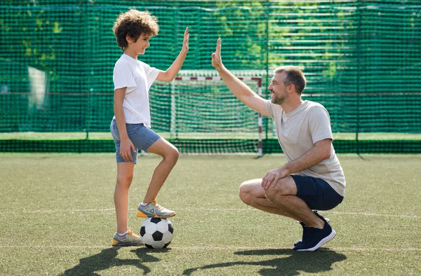 Happy father playing football on a field with son — Stock Photo, Image