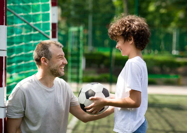 Happy father playing football on a grass with son — Stock Photo, Image