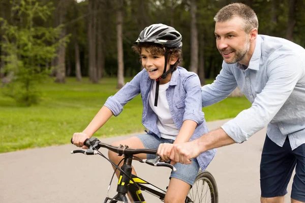 Boy learning to ride a bicycle with his father — Stock Photo, Image