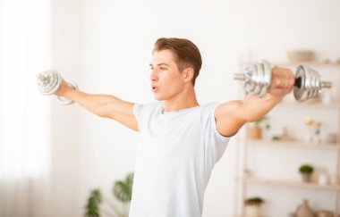 Kendini izole et ve formda kal. Kas yığını adam gün ışığında halterleri kaldırıyor.