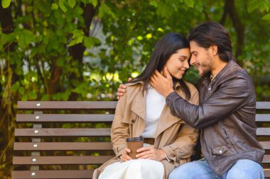 Genç çift parkta bankta oturuyor.