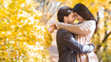 Romantik çift ormanda flört ederken birbirlerine sarılıyorlar.