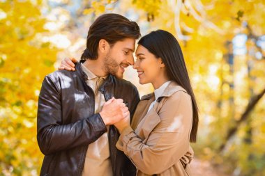 Sarılan çiftler, altın ağaçların üzerinde el ele tutuşuyorlar.