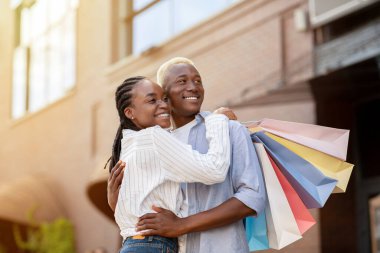 Birlikte eğlenin ve alışveriş yapın. Gülümseyen çift çantalarla geziyor.