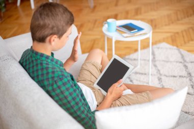 Boş ekranla dijital tablete el sallayan çocuk