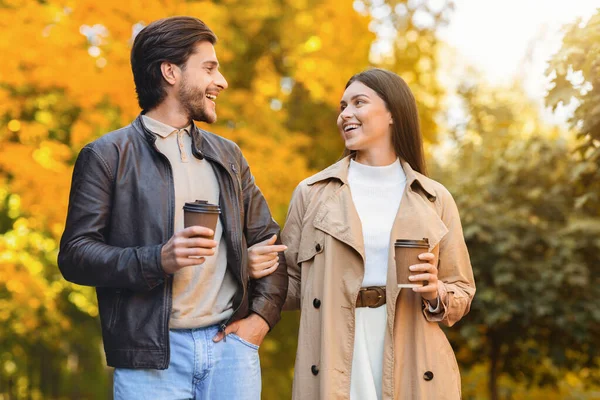 Homem e mulher bebendo café enquanto caminham pela floresta dourada — Fotografia de Stock