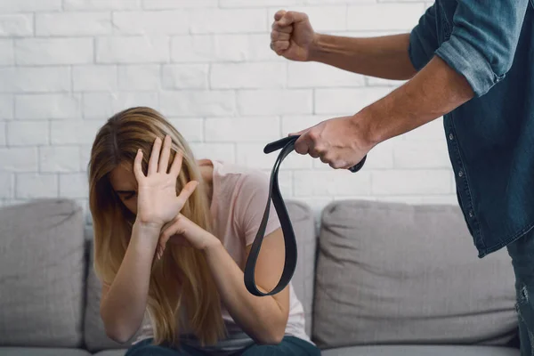 Menaces et violence physique. L'homme en colère menace de poing et de ceinture à la femme effrayée — Photo