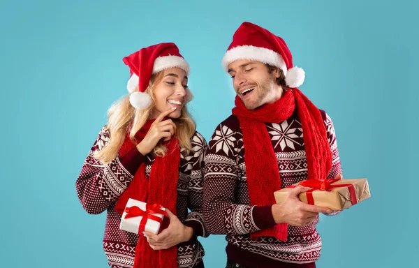 Ritratto di giovane coppia affettuosa in abiti natalizi con scatole regalo su sfondo blu — Foto Stock