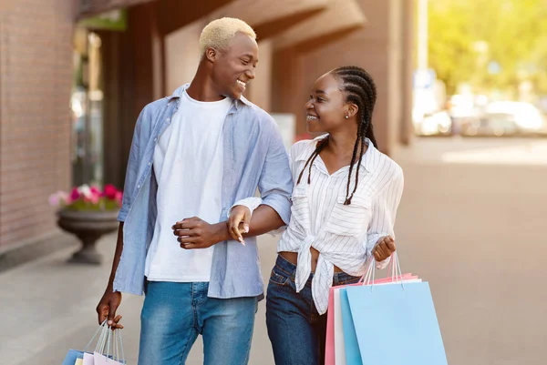Winkelreis. glimlachend Afrikaans Amerikaans paar met papieren zakken kijken elkaar aan — Stockfoto