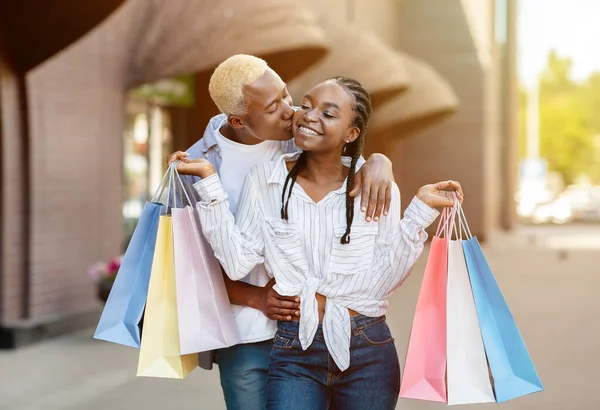 Lifestyle en shopping concept. Vreugdevol Afrikaans amerikaanse jongen zoenen meisje — Stockfoto