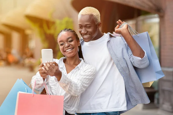 Samen wandelen, winkelen en selfies maken in de stad. Vrolijk Afrikaans Amerikaans man en vrouw nemen foto op smartphone — Stockfoto