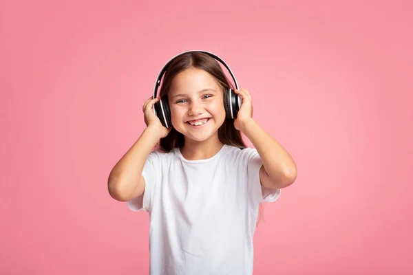 Música e dispositivo favoritos. Menina feliz bebê segura em fones de ouvido na cabeça — Fotografia de Stock