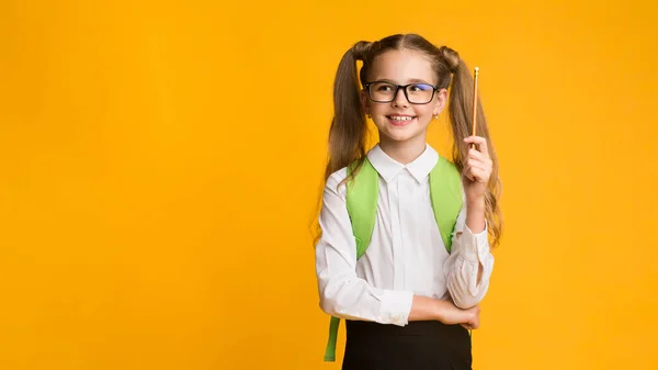 Colegiala señalando lápiz hacia arriba tener idea sobre fondo amarillo, Panorama — Foto de Stock