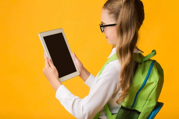 Školní dívka s tabletem pomocí vzdělávací aplikace, žluté pozadí, Mockup — Stock fotografie