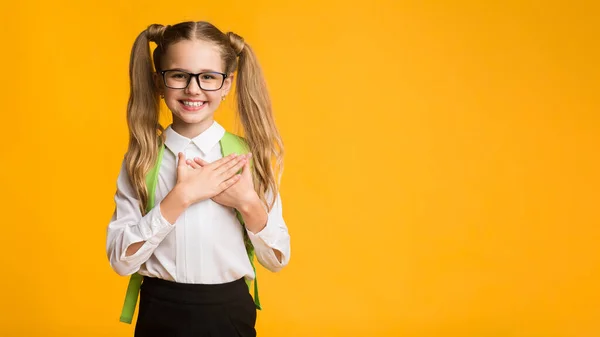 Školačka stisk ruce na hruď vyjádření vděčnosti na žlutém pozadí — Stock fotografie