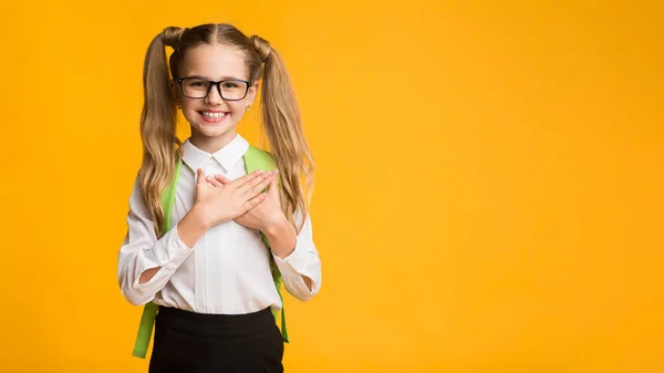 Studentessa premendo le mani al petto esprimendo gratitudine su sfondo giallo — Foto Stock