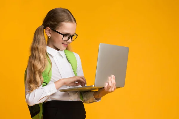 Schoolmeisje met behulp van Laptop Computer Studeren Online, gele achtergrond, Studio Shot — Stockfoto