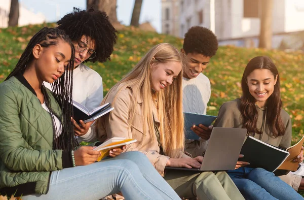 Students studying hard, sitting on the ground at park