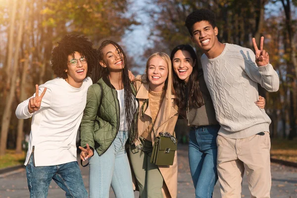 Весёлые многоэтнические подростки улыбаются в камеру на улице — стоковое фото