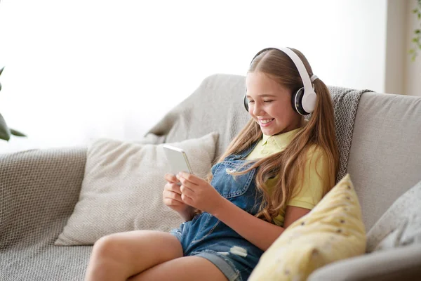 Flicka i hörlurar njuter av musik med telefon — Stockfoto