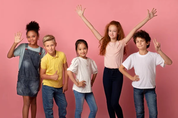 Coole multiethnische Schüler, die verschiedene Gesten auf rosa Hintergrund zeigen — Stockfoto