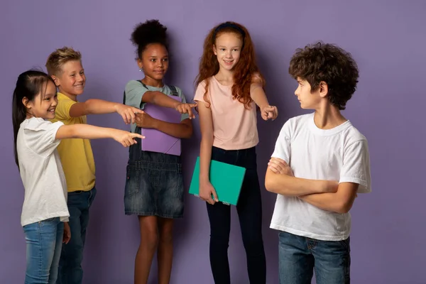 Vicious schoolkids bullying their upset classmate on violet background — Stock Photo, Image