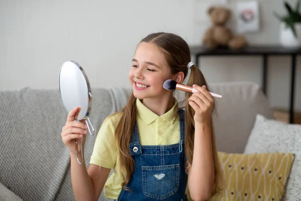 Ung flicka gör smink, håller och tittar på spegel — Stockfoto