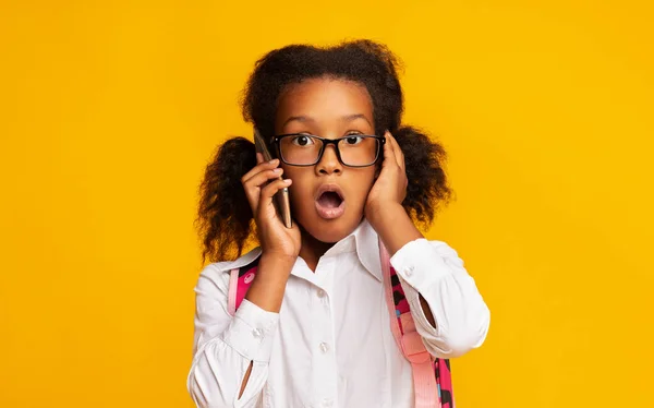 Šokovaný školní dívka mluví na telefonu s otevřenými ústy, Studio — Stock fotografie