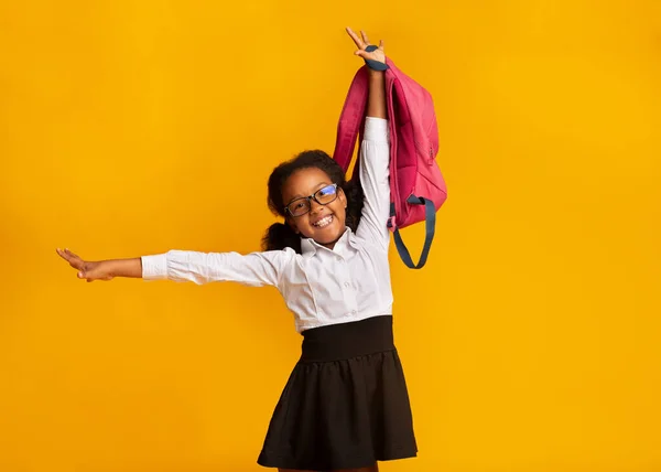 快乐的非洲女学生背包挂在黄色工作室的背景下 — 图库照片