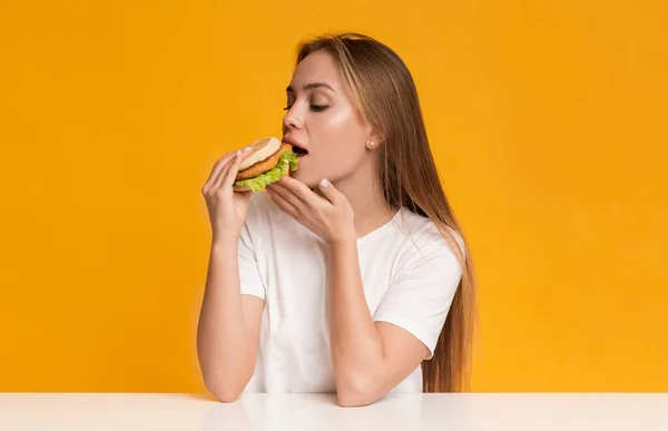 チート・ミール。食欲をそそるバーガーを食べる空腹千年紀の女の子 — ストック写真